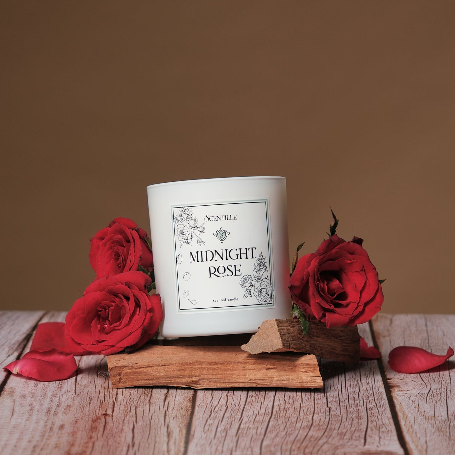 A Midnight Rose candle on wood surrounded by rose petals