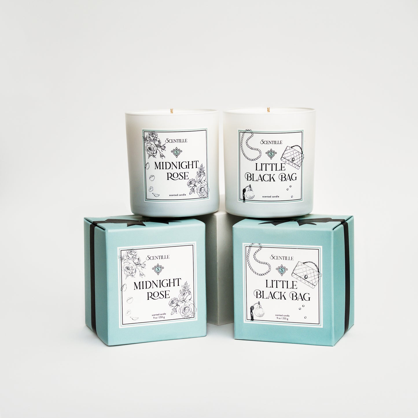 Two candles in boxes labeled 'Midnight Rose' and 'Little Black Bag' on a white background