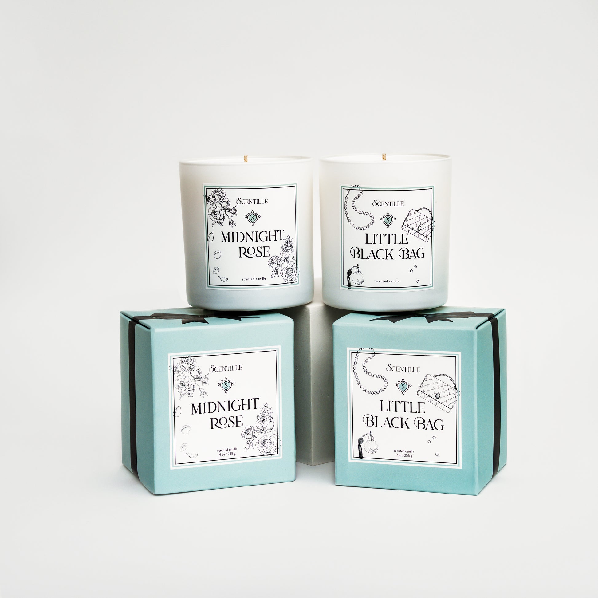 Two candles in boxes labeled 'Midnight Rose' and 'Little Black Bag' on a white background