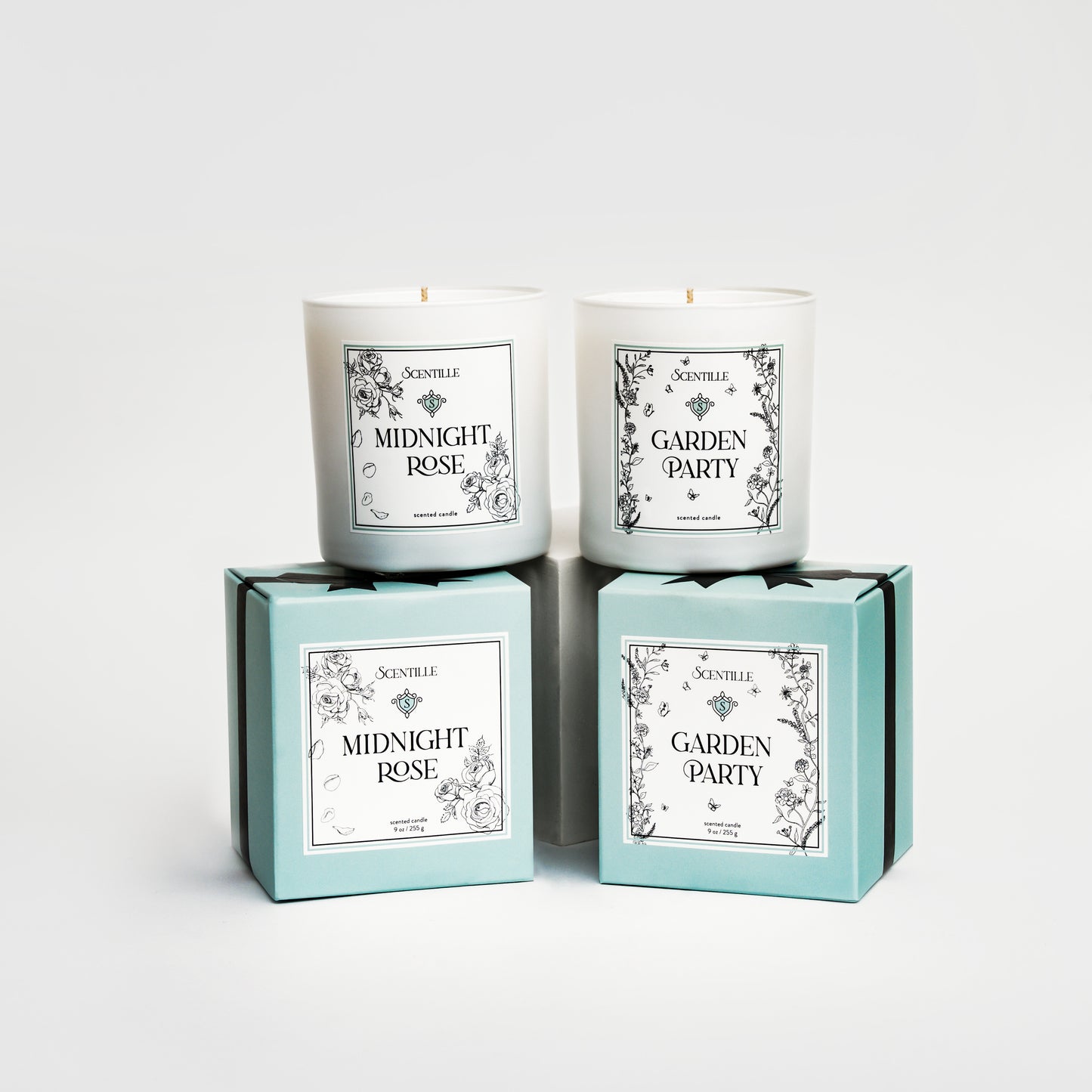 Two candles named 'Midnight Rose' and 'Garden Party' in their packaging on a white background.