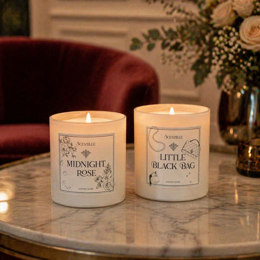 Two lit candles labeled 'Midnight Rose' and 'Little Black Bag' on a marble table.