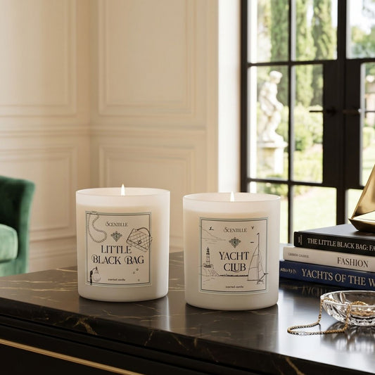 Two candles labeled 'Little Black Bag' and 'Yacht Club' on a table with decorative items.
