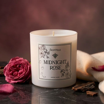 Candle labeled 'Midnight Rose' with a pink rose and decorative elements on a dark surface.