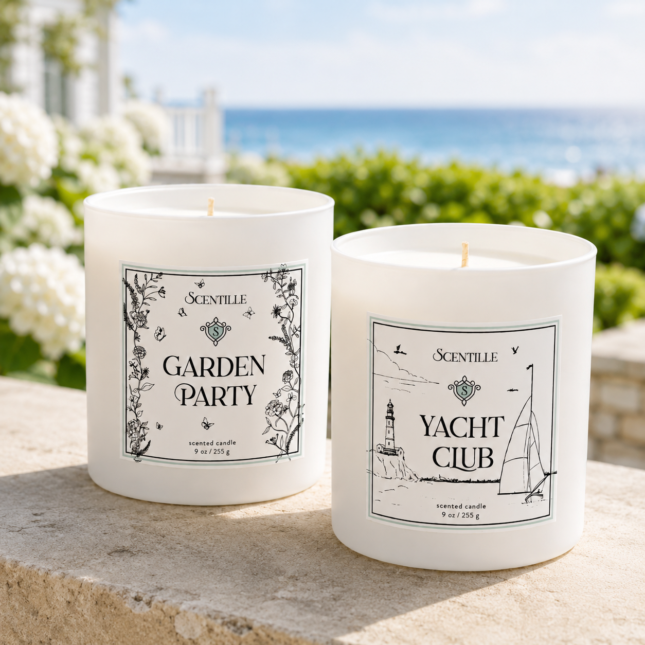 Two Scentille scented candles in white glass jars are displayed outdoors on a stone ledge with a blurred garden and ocean background. The left jar is labeled 'GARDEN PARTY' with botanical illustrations, and the right jar is labeled 'YACHT CLUB' with nautical line drawings.